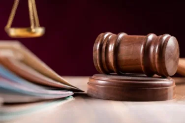 Marteau de juge à côté de documents et d'une balance en métal doré.