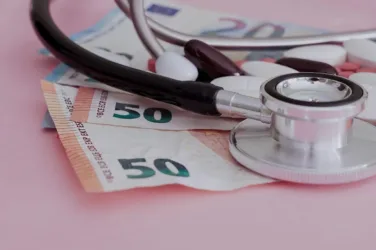 Photo d'un stéthoscope et de médicaments posés sur des billets en euros.