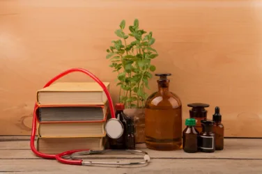 Des objets posés symbolisent différentes formes de médecine : plante, bocaux, stéthoscope, livres.