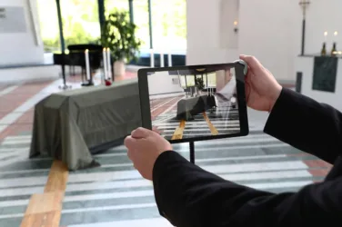 Un homme tient une tablette photographiant un cercueil.