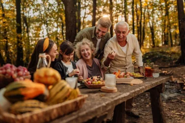 Une famille, sur trois générations, passe un moment de convivialité en forêt, lors d'une journée d'automne.